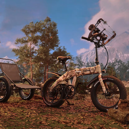 JupiterBikes_Green camouflage-patterned Defiant electric bike with a trailer in a forest setting with mountains in the background