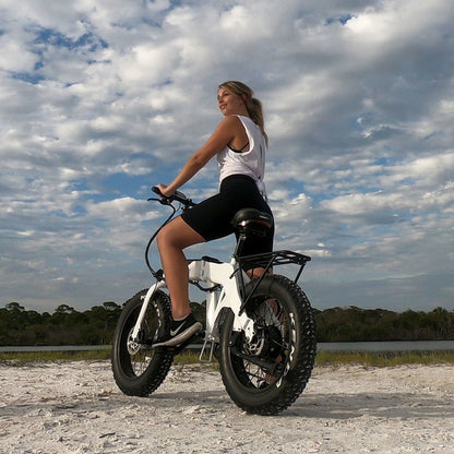 JupiterBikes_Young lady riding a fat-tire e-bike called Defiant on a dirt/sandy path with a cloudy sky in the background