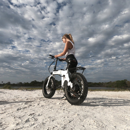 Jupiter_Young lady riding a white electric bike (Defiant) on a sandy terrain with a cloudy sky
