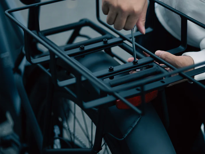 Velowave_Person using a tool (screwdriver) to adjust a bike rack on a bicycle