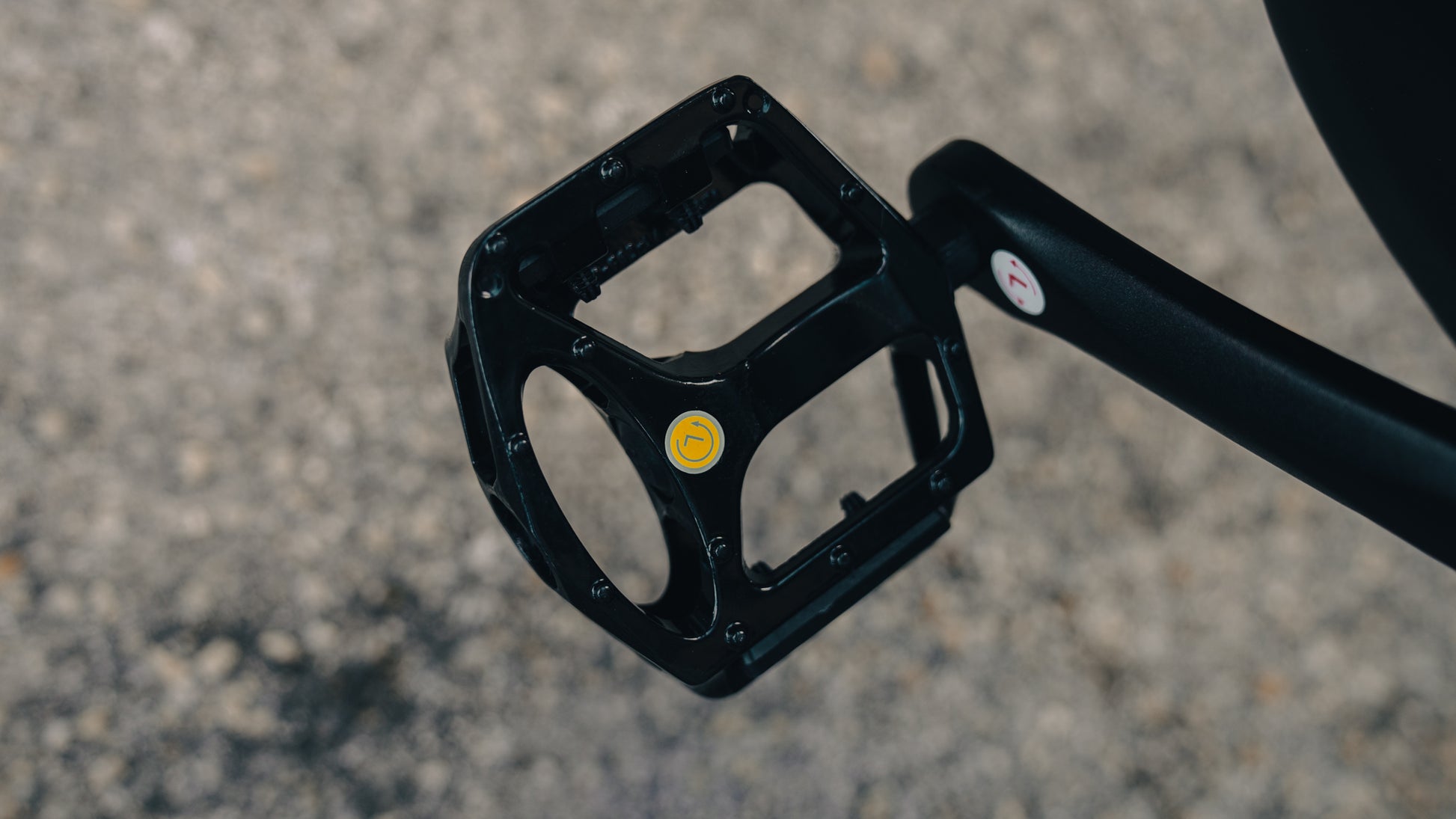 velowave_Close-up of a black electric bicycle pedal on a gray pavement background