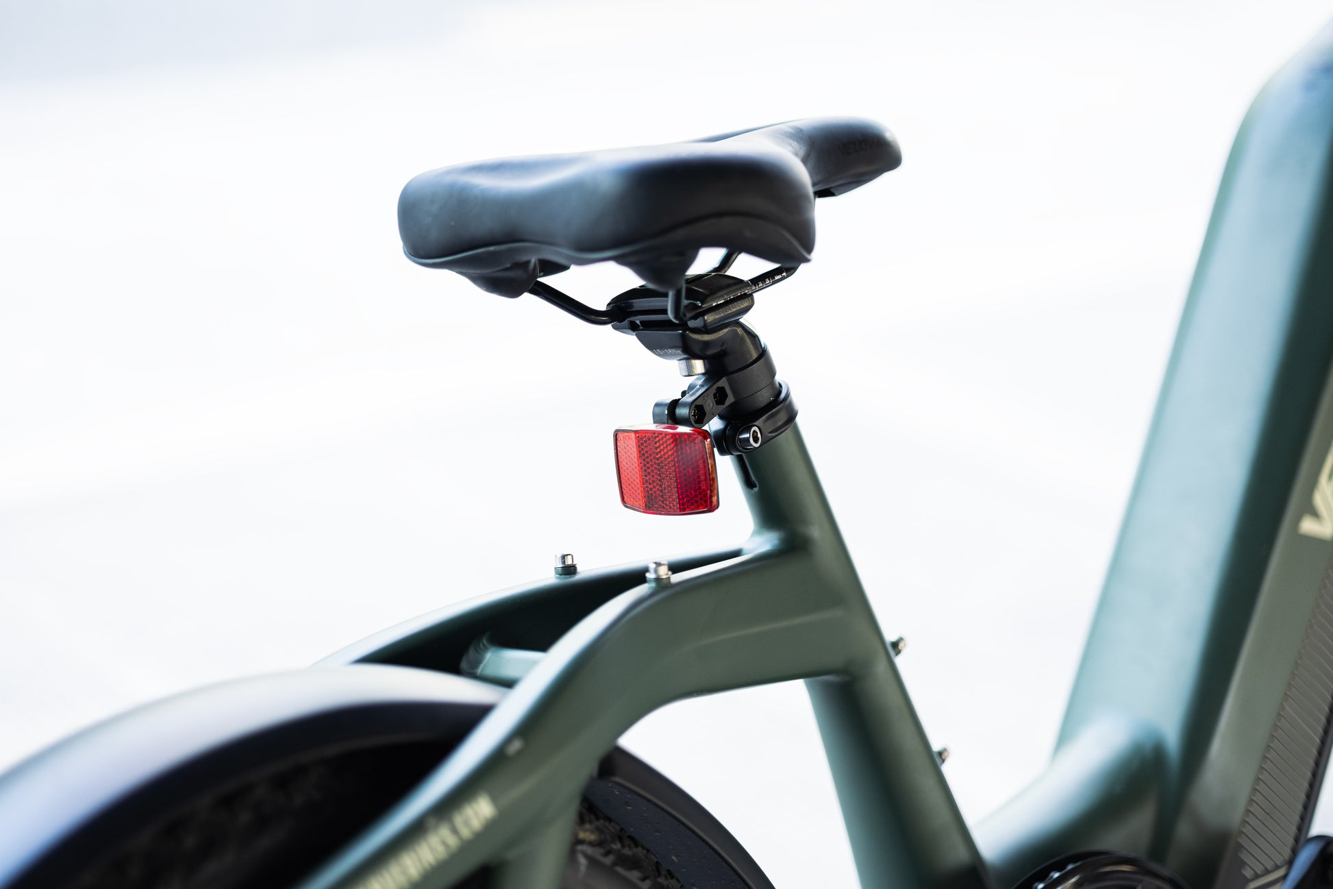 velowave_Close-up of a Green Pony electric bicycle seat and frame with a red taillight on a blurred background