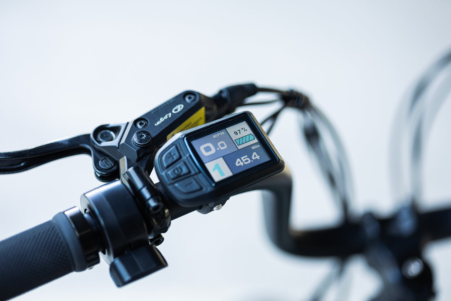 velowave_Close-up of the Pony electric bicycle handlebar with digital display and brake lever on a blurred background