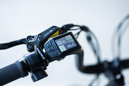 velowave_Close-up of the Pony electric bicycle handlebar with digital display and brake lever on a blurred background