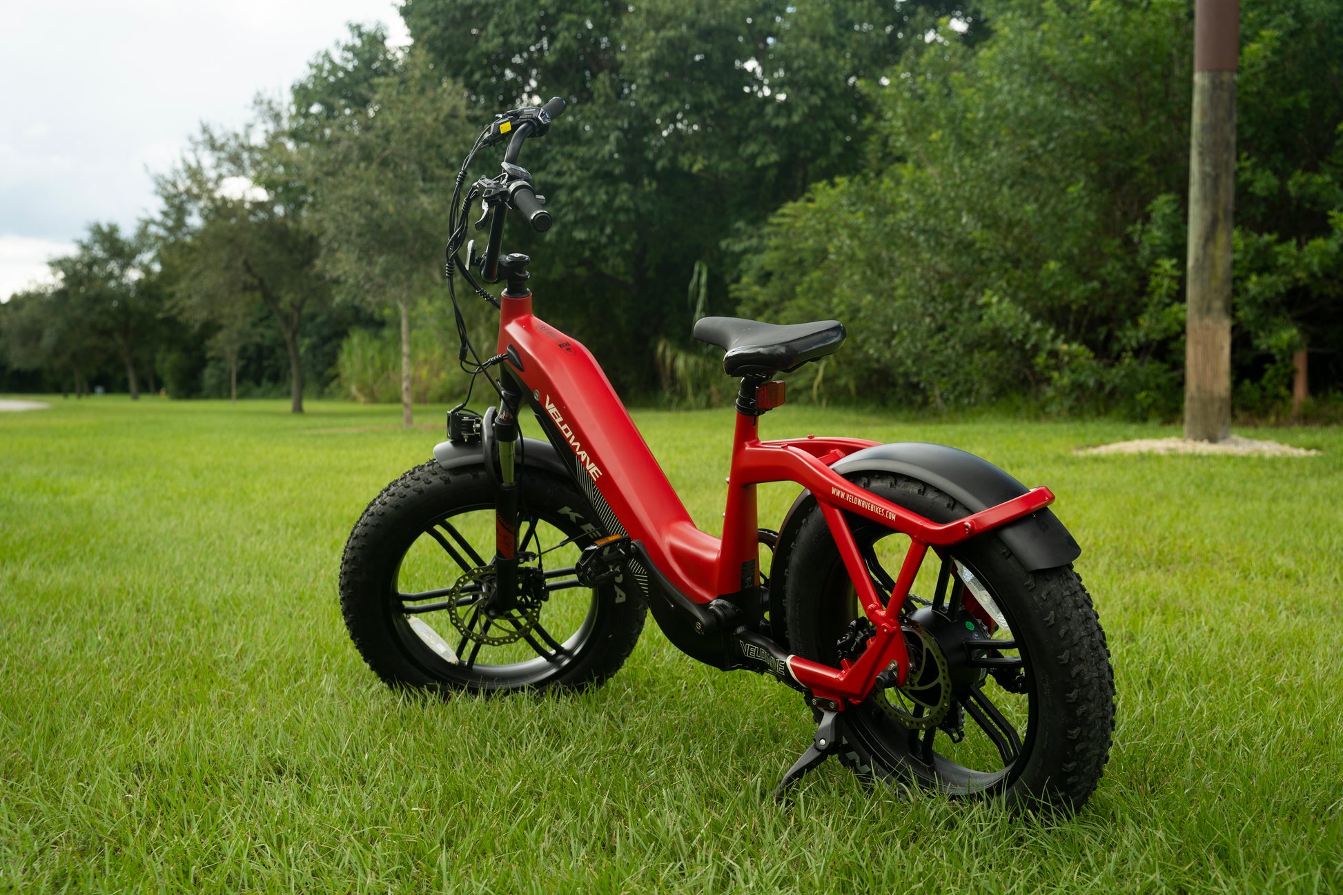 velowave_Red Pony electric bike on grass with trees in the background