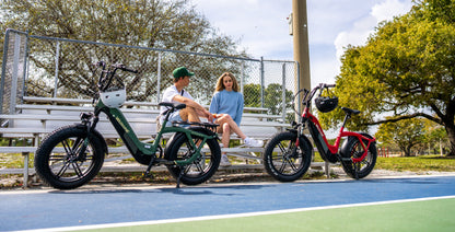 velowave_Two Pony electric bikes on a basketball court with people sitting on a bench.