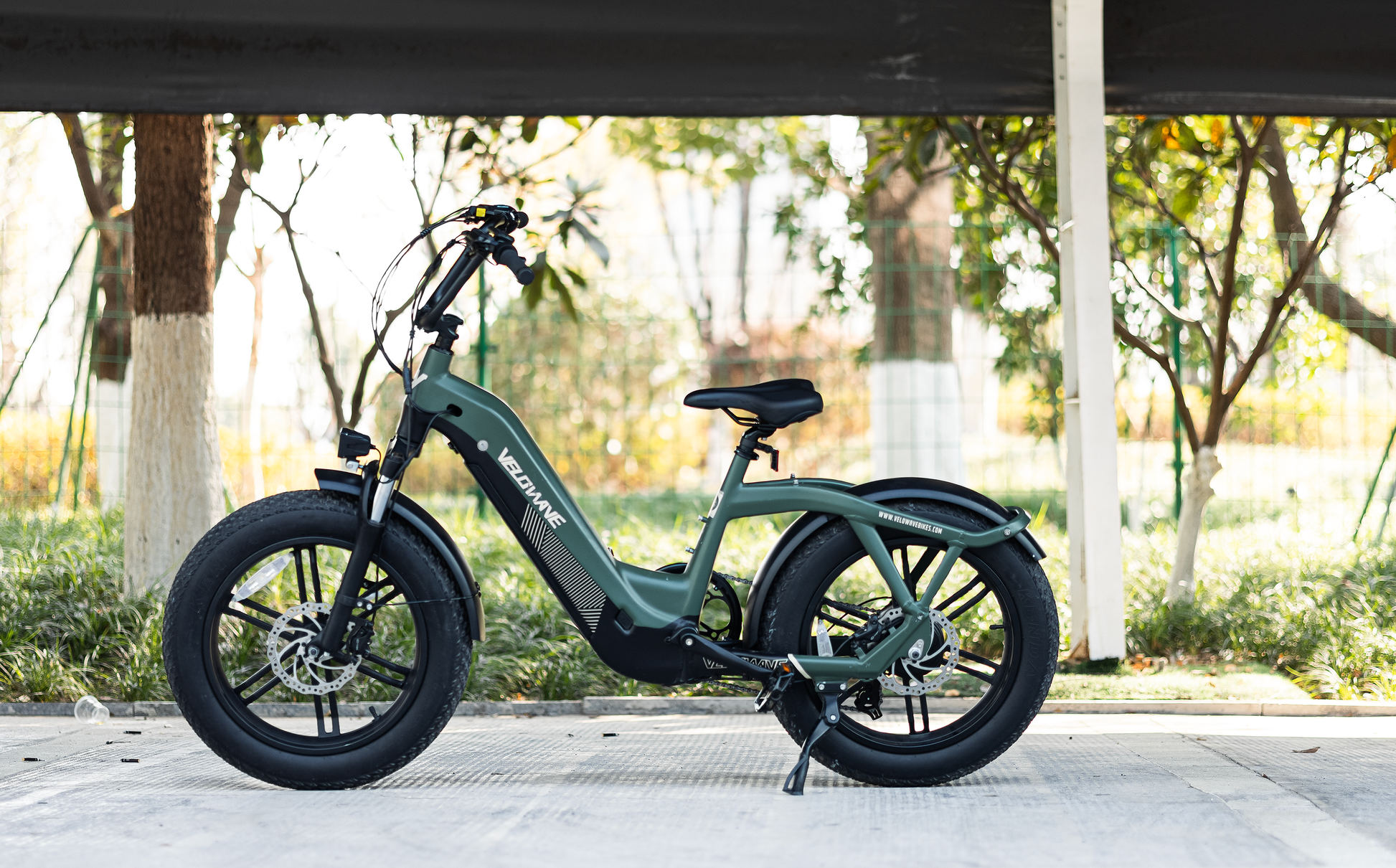 velowave_Green electric bike on a paved path with trees in the background