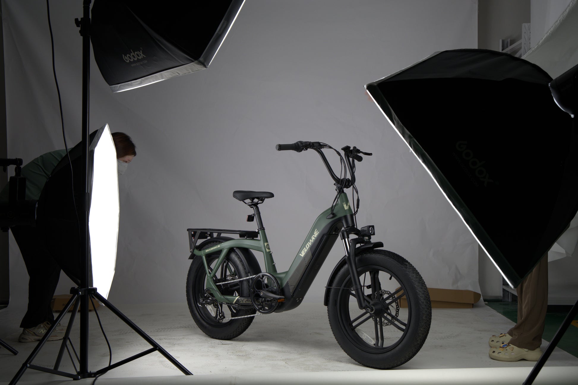velowave_Pony green electric bike on a white platform with photography equipment and studio lights.